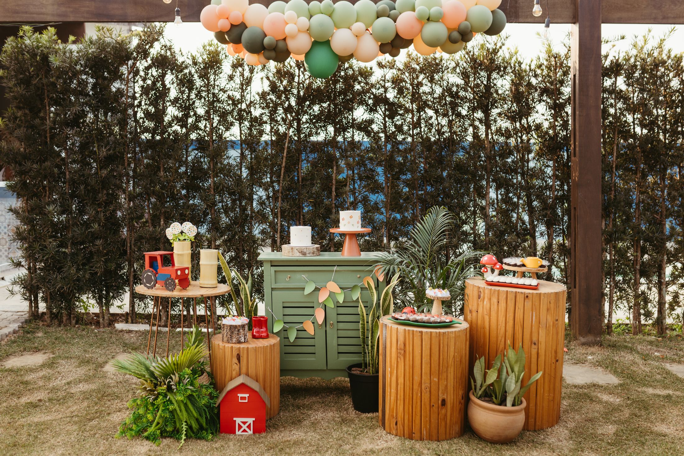 Outdoor celebration with colorful balloons, natural greenery, and decorated party tables