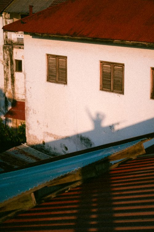 Free Warm tones capture a playful shadow on a rustic house wall at sunset. Stock Photo