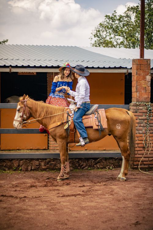 Free Two people in traditional attire riding a horse at a ranch in Mexico City. Stock Photo
