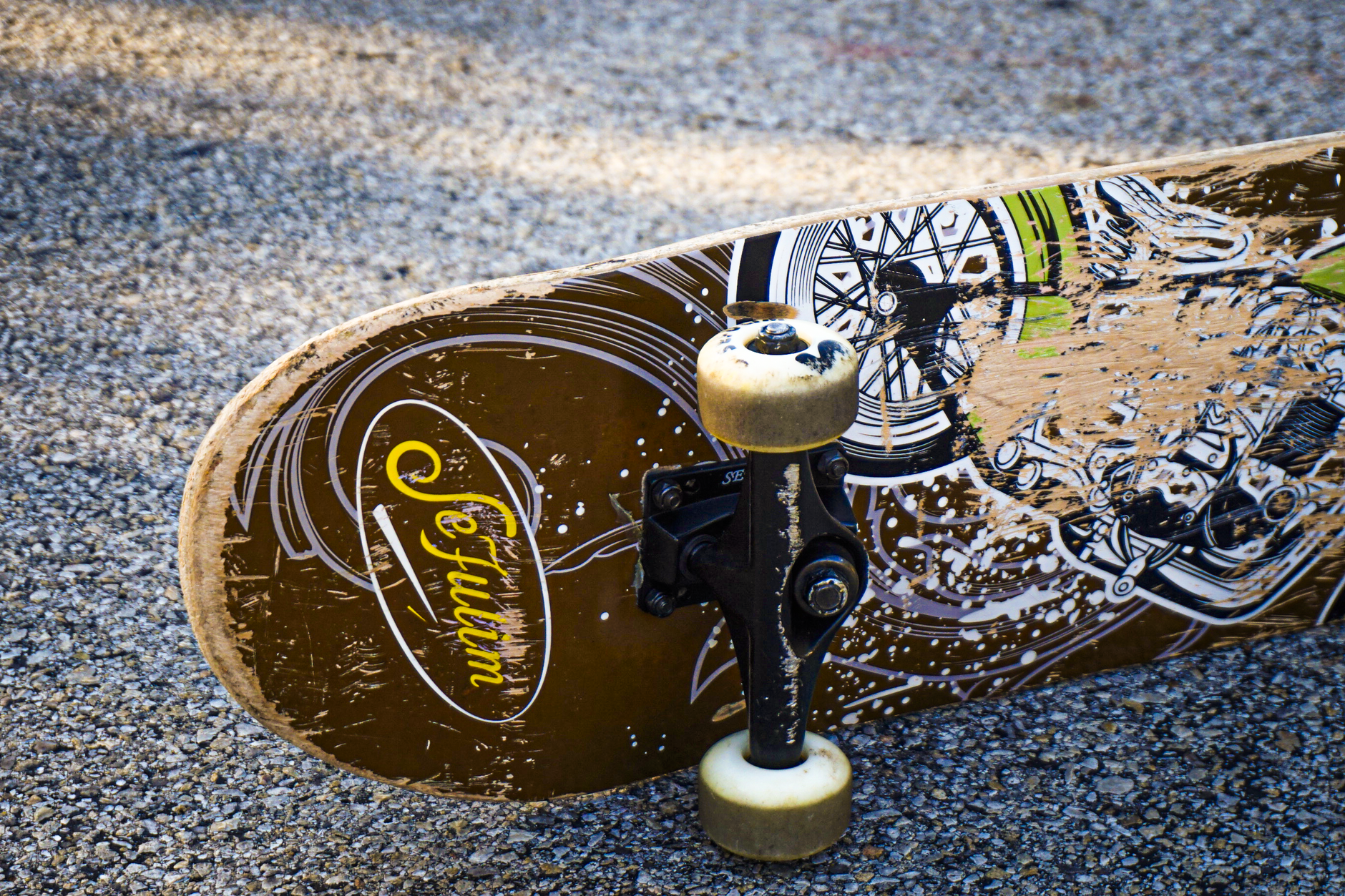 Close-up of a vintage skate deck with faded Cockfight Skateboards artwork on a Houston garage wall