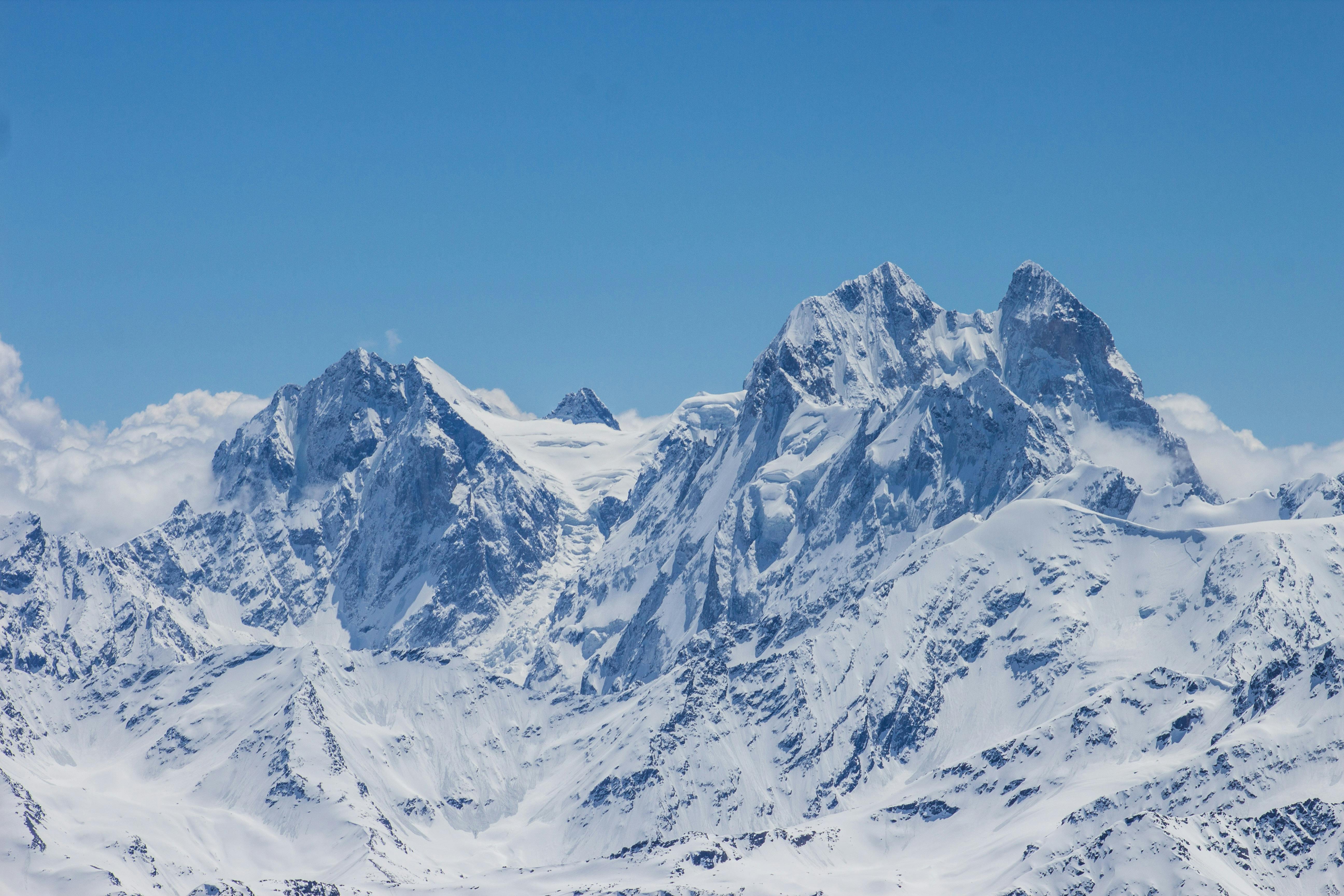 Stunning view of snow-covered mountains under a clear blue sky, showcasing winter scenery.