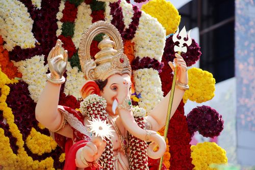 Free A colorful statue of Lord Ganesha adorned with vibrant flowers at an outdoor festival. Stock Photo