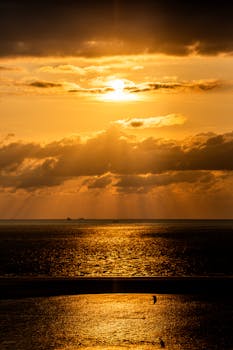 Dramatic sunset over the North Sea viewed from Borkum in Germany, with golden light and serene waves.