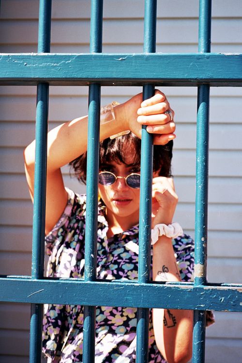 Free Stylish woman in sunglasses poses behind blue bars on a sunny day. Stock Photo