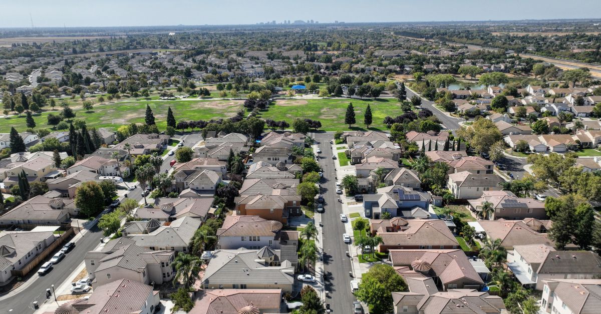 Scenic aerial view of Sacramento suburb with rows of houses and lush greenery on a sunny day.
