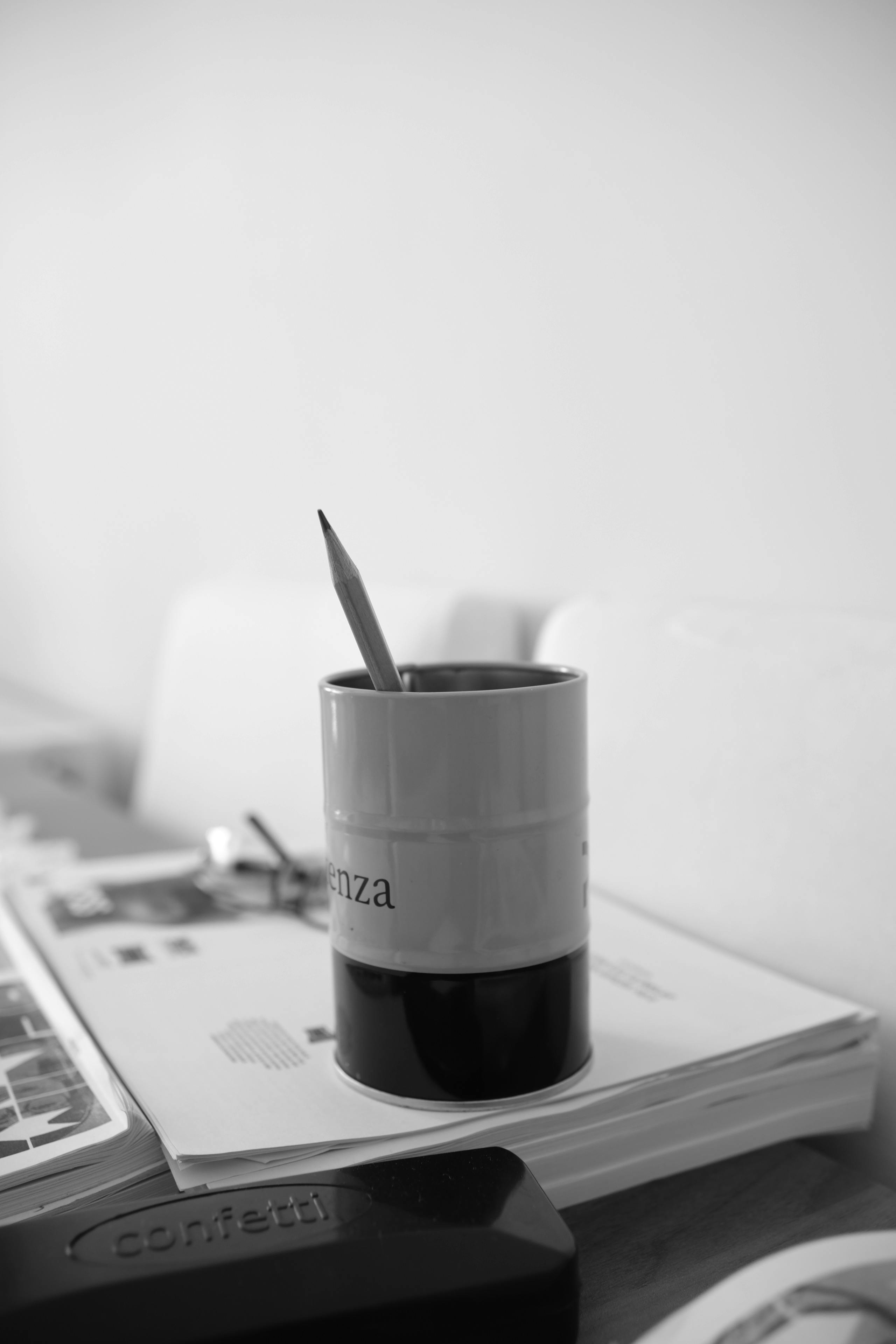 Free Black and white photo of a desk with a pencil in a holder and a stapler, creating a classic office vibe. Stock Photo