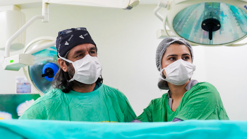 Free Two medical professionals focused during surgery in a sterile operating room environment. Stock Photo