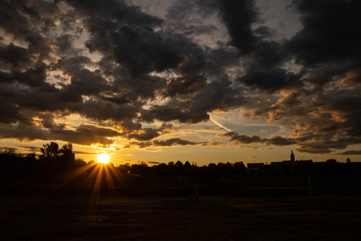 A breathtaking view of the sun setting over a rural landscape with dramatic cloud formations.
