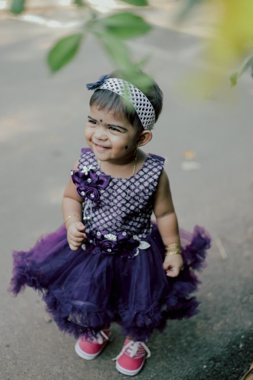 Free Cute toddler smiling in a purple dress and headband outdoors. Stock Photo