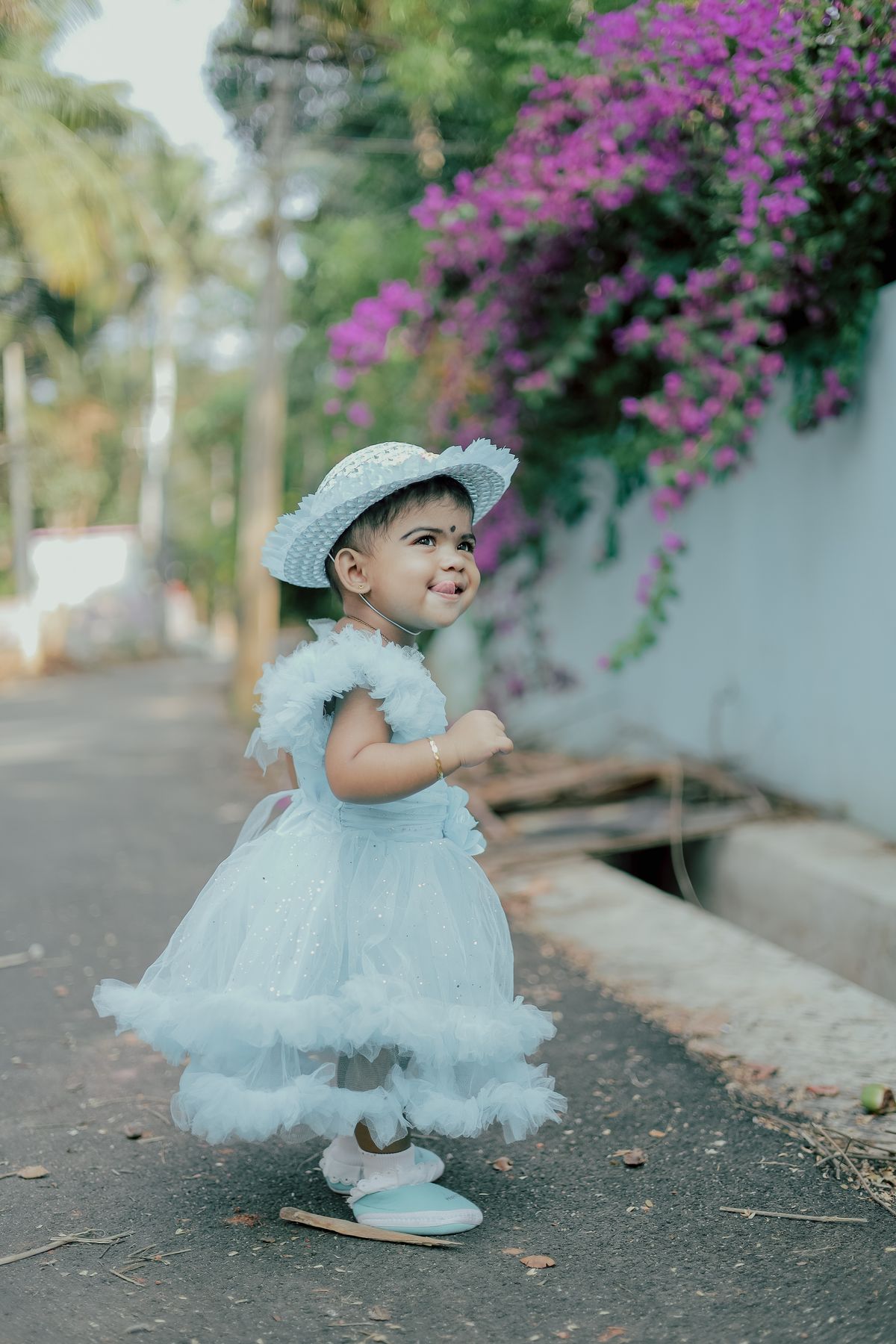 Toddler in a white dress with a hat outdoors