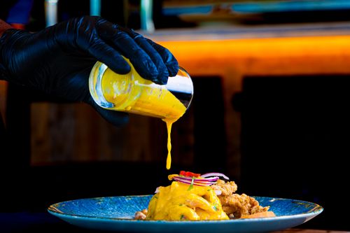 Free Chef pouring vibrant yellow sauce on gourmet dish. Perfect for culinary and food photography. Stock Photo