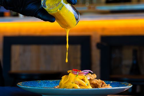 Free Close-up of cheese sauce dripping onto elegant dish, highlighting gourmet presentation. Stock Photo