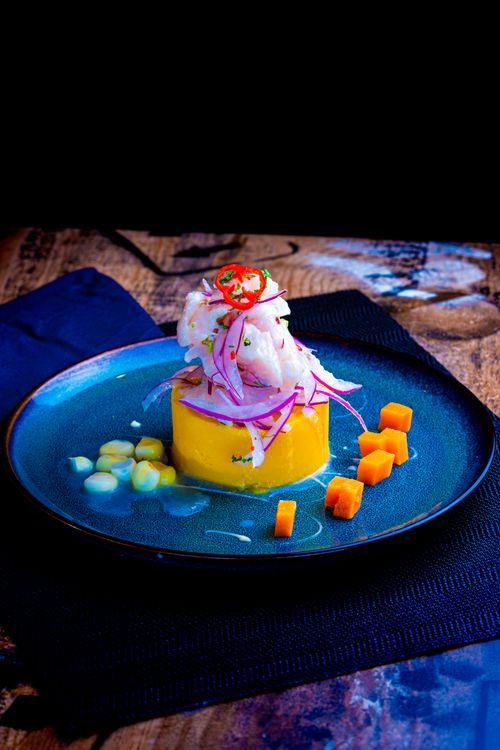 Free Plate of Peruvian causa topped with ceviche, garnished elegantly for gourmet appeal. Stock Photo