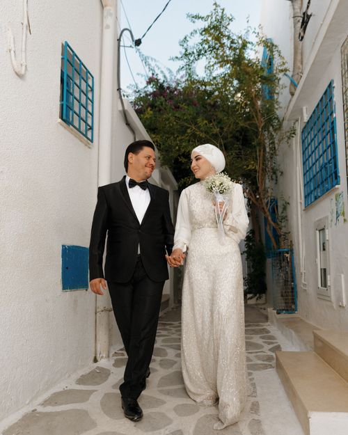Free Elegant couple walking hand in hand in the charming streets of Hammamet, Tunisia. Stock Photo