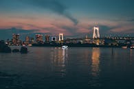 东京黄昏的城市景观令人惊叹，彩虹桥倒映在宁静的水面上