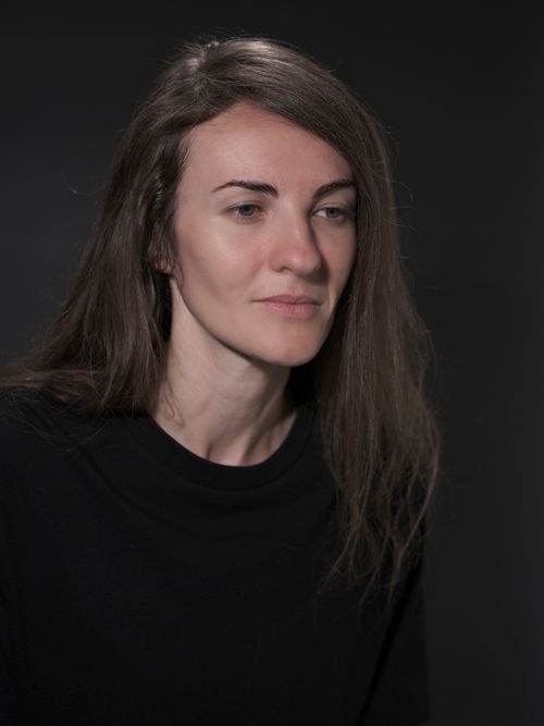 Free A calm and introspective studio portrait of a woman with long hair wearing a black top, on a dark background. Stock Photo