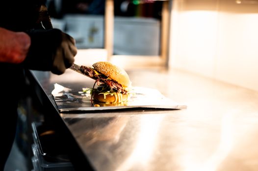 Chef placing a freshly made gourmet burger on a counter in a modern kitchen. Captured with a NIKON Z 6.