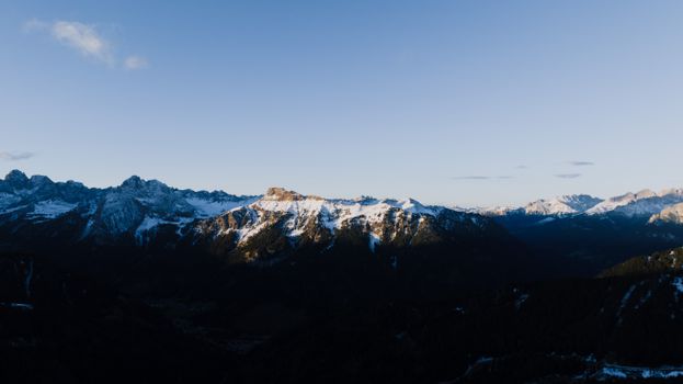 Stunning panoramic view of snow-capped Dolomites in Canazei, Italy under a serene evening sky.