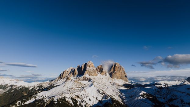 Stunning view of snow-capped Dolomites in Canazei, Italy under a clear blue sky.