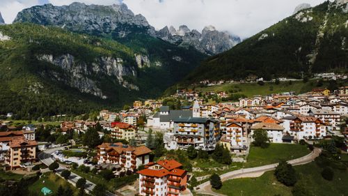 Free Scenic aerial view of Molveno village nestled in the Italian Alps featuring charming architecture and lush mountains. Stock Photo