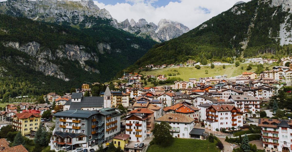 A picturesque view of Molveno village nestled at the base of the Dolomites in Italy, showcasing vibrant architecture and lush landscapes.