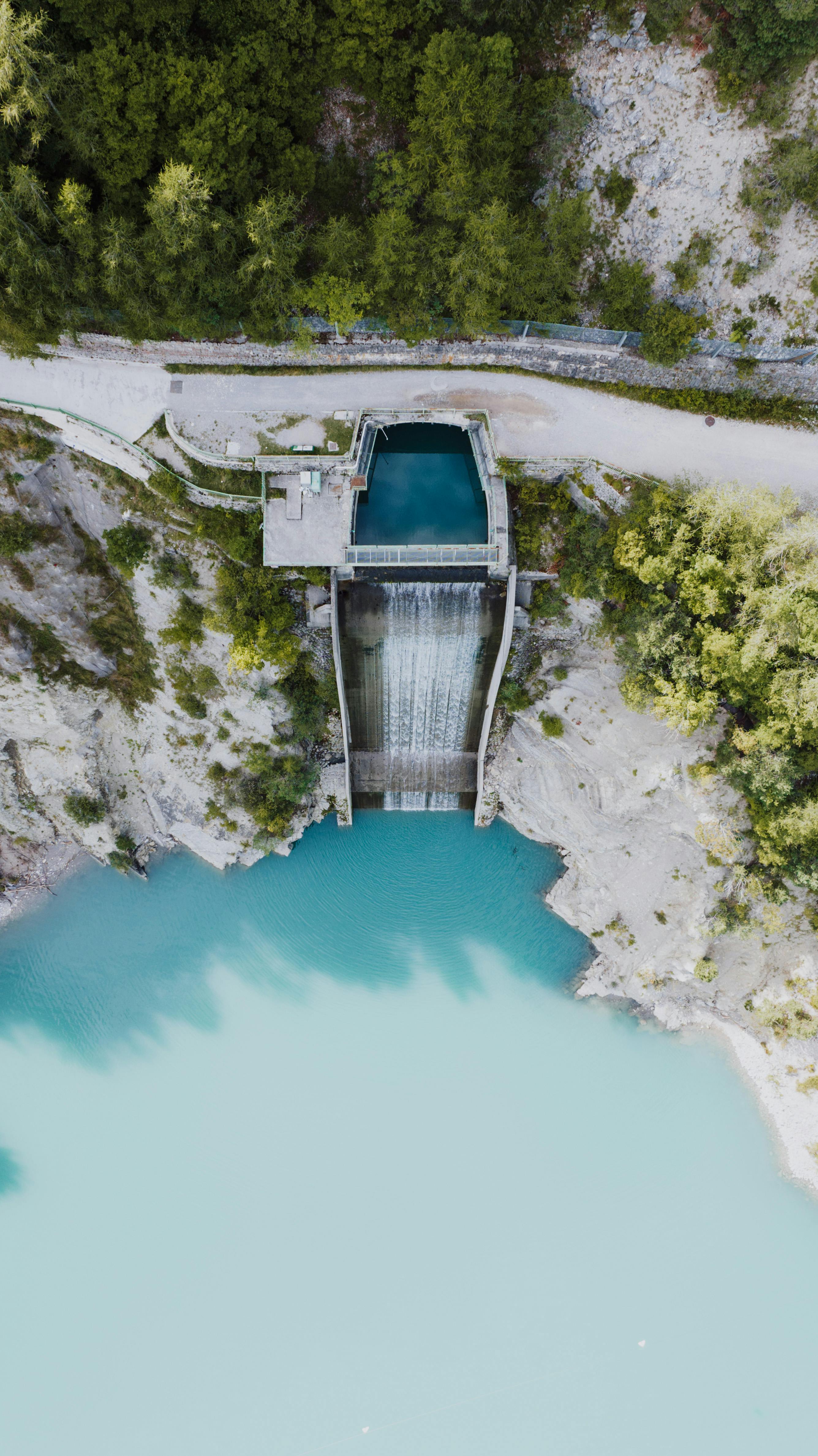 Aerial shot of a dam surrounded by lush forest in Molveno, Trentino-Alto Adige, Italy.