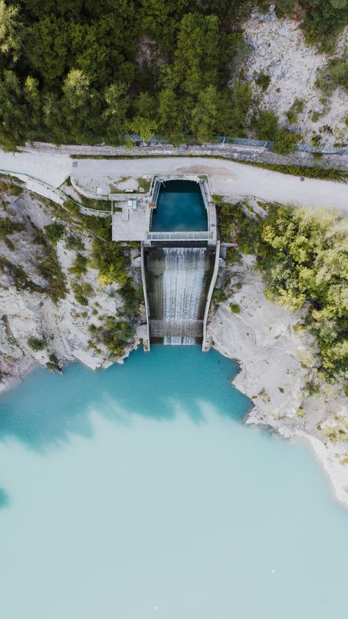 Free Aerial shot of a dam surrounded by lush forest in Molveno, Trentino-Alto Adige, Italy. Stock Photo