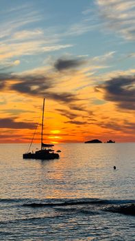A stunning silhouette of a catamaran at sunset on the Ibiza coastline, Spain.
