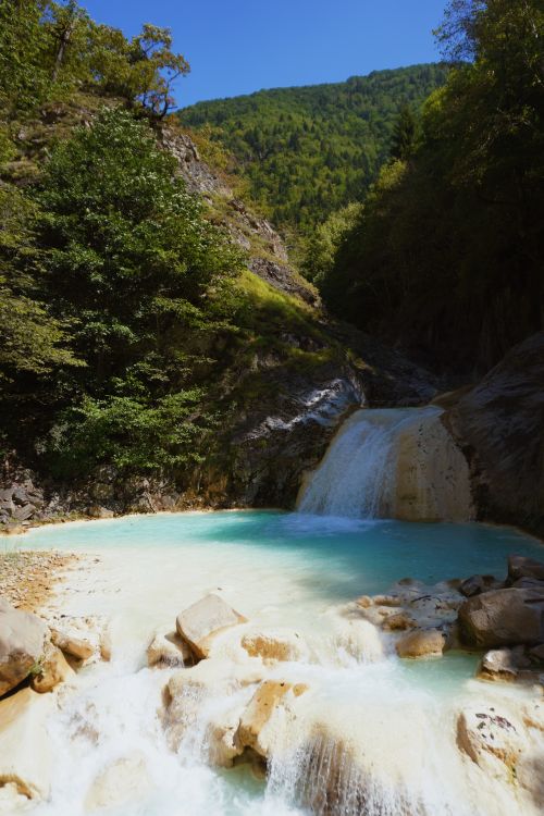 Free Captivating view of a clear turquoise waterfall in a verdant mountain setting, offering tranquility and natural beauty. Stock Photo