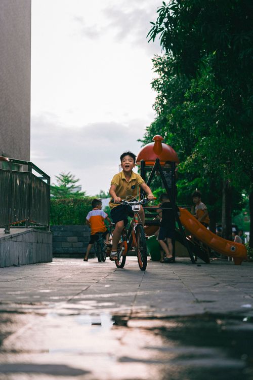 Free A young boy joyfully rides his bicycle in a vibrant urban playground environment. Stock Photo