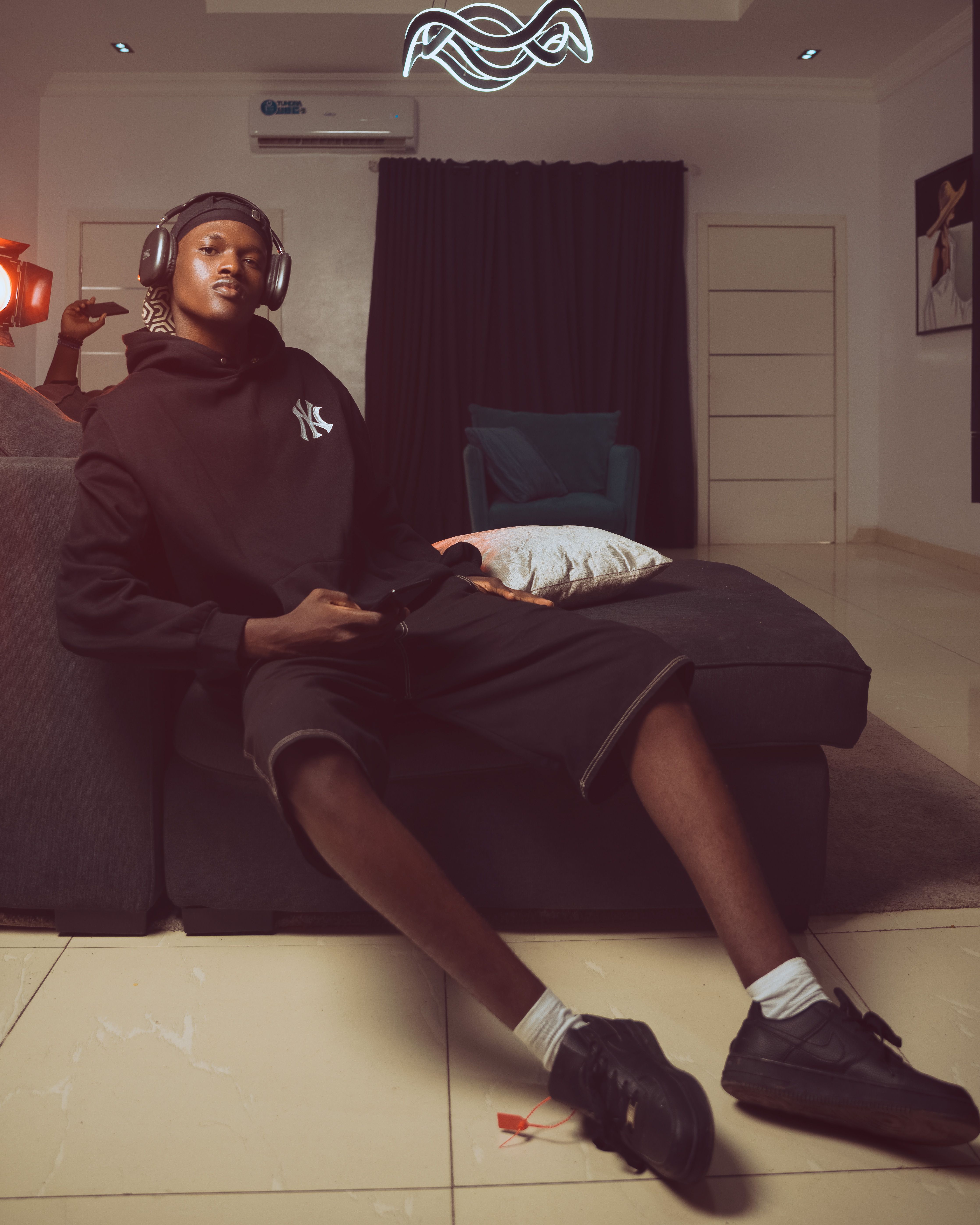Teenager relaxing with headphones on couch at home, enjoying music.