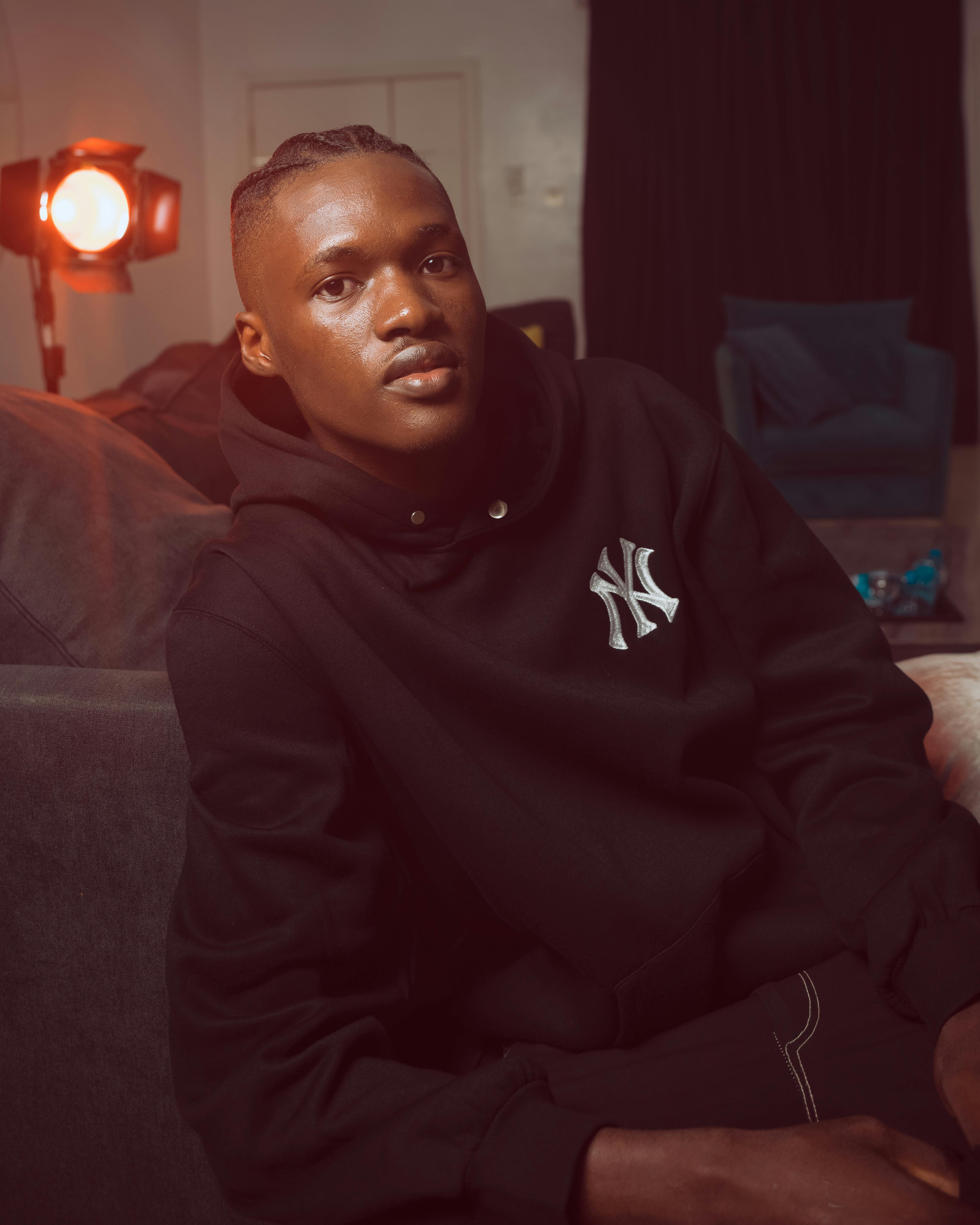 Relaxed young man in a hoodie at home with warm lighting.