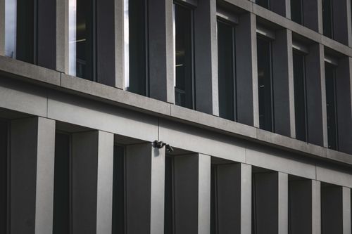 Free Contemporary office building exterior featuring multiple windows and security cameras. Stock Photo