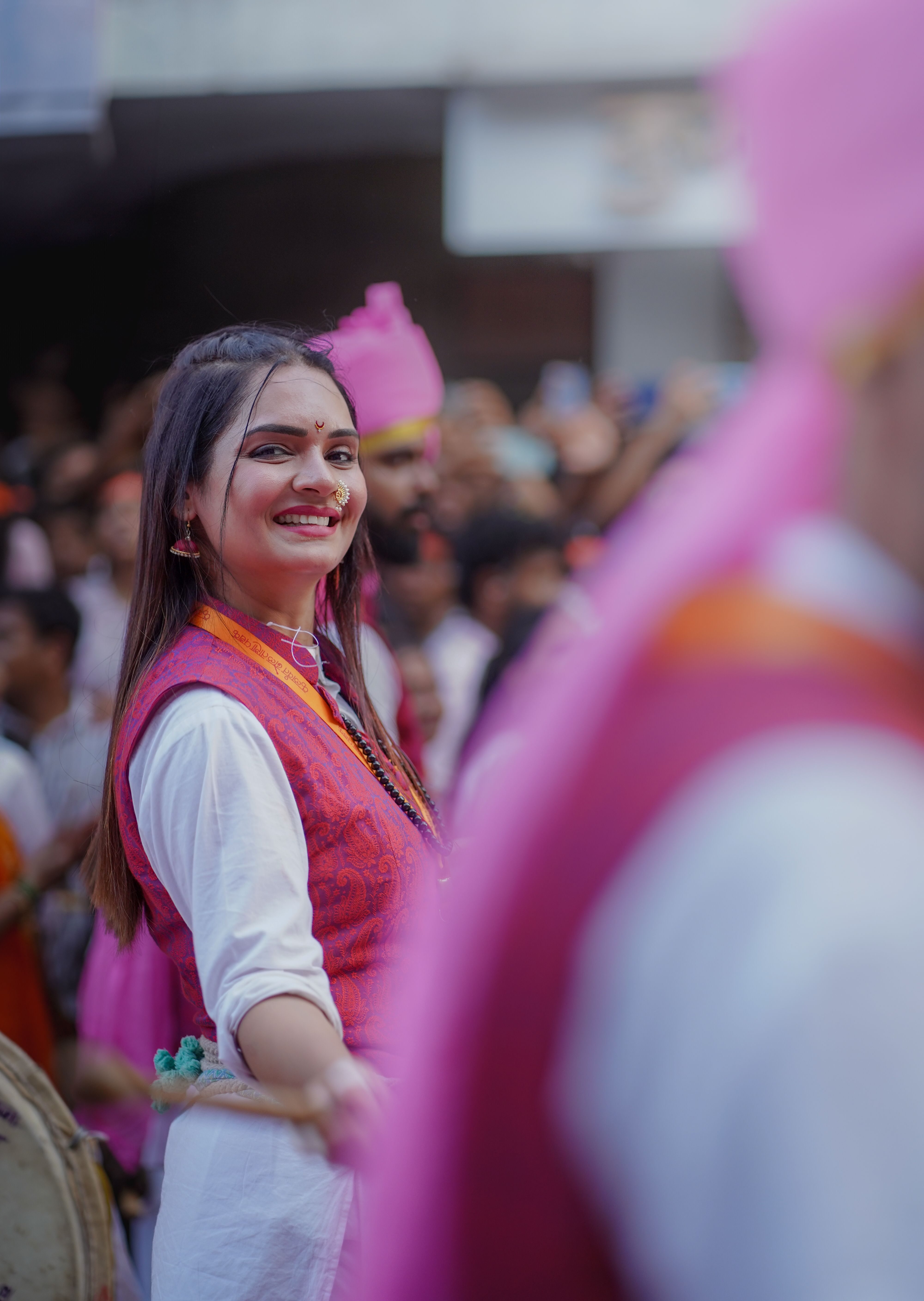 A joyful woman participating in a lively festival parade in Pune, India, showcasing vibrant colors and cultural attire.