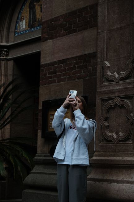Young woman capturing moments on her phone in an urban setting.