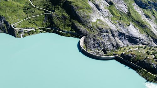 Free Stunning aerial view of a dam surrounded by emerald waters and rugged mountains in Korutany, Austria. Stock Photo