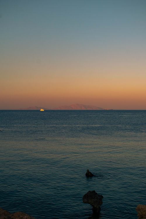 Free Tranquil beach sunset overlooking a calm ocean, evoking peaceful summer vibes. Stock Photo