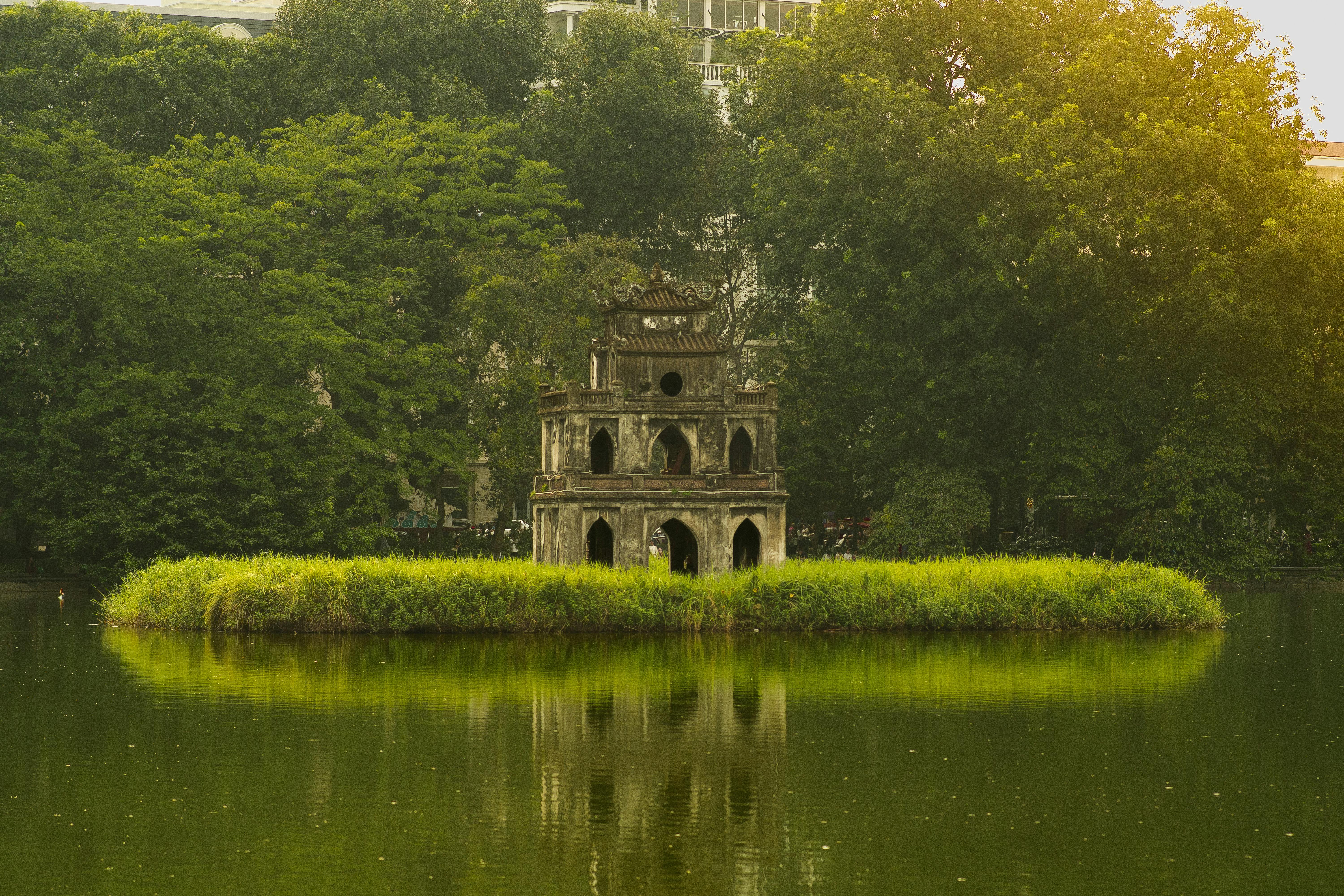 Serene view of Turtle Tower in Hanoi's Hoan Kiem Lake surrounded by lush greenery.