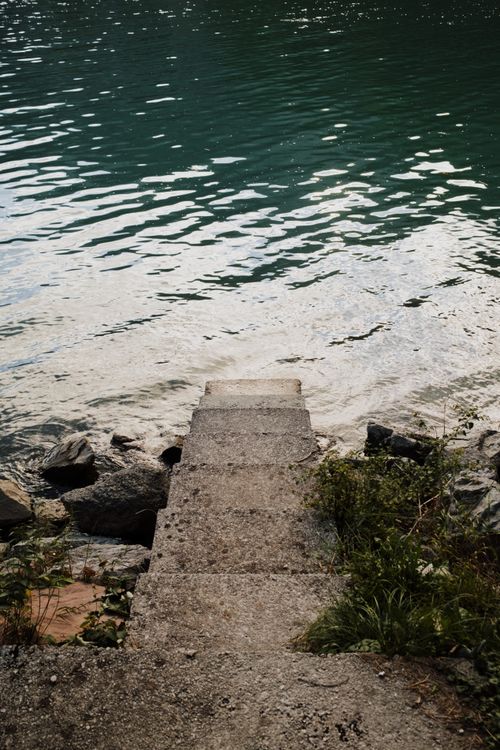 Free Concrete steps descending into Lake Molveno in Trentino-Alto Adige, Italy, reflecting tranquil waters. Stock Photo