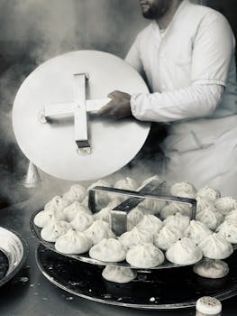 Chef in uniform steaming dumplings in a commercial kitchen setting.