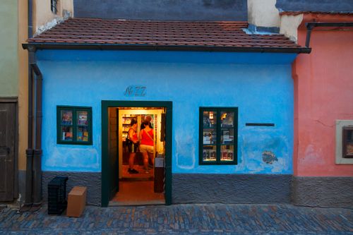Free Charming blue house on a cobblestone street with a warmly lit interior in Prague. Stock Photo