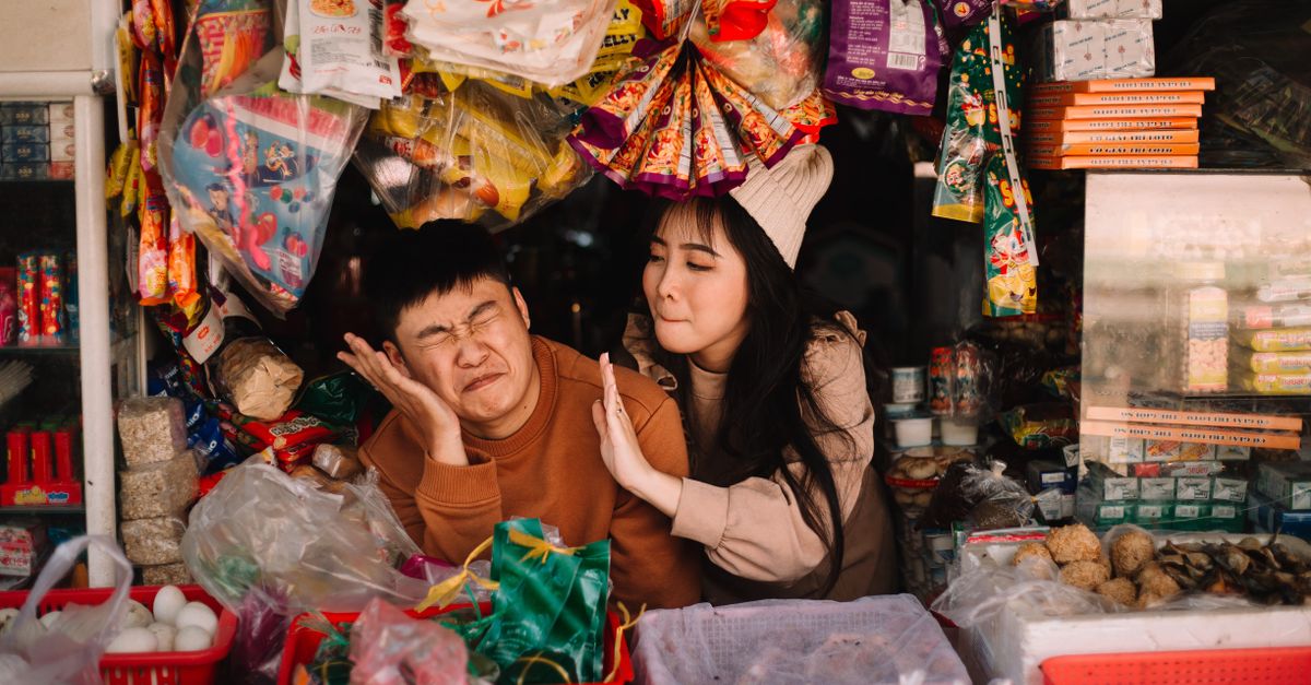 group of vendors laughing together while arranging goods in a market stall