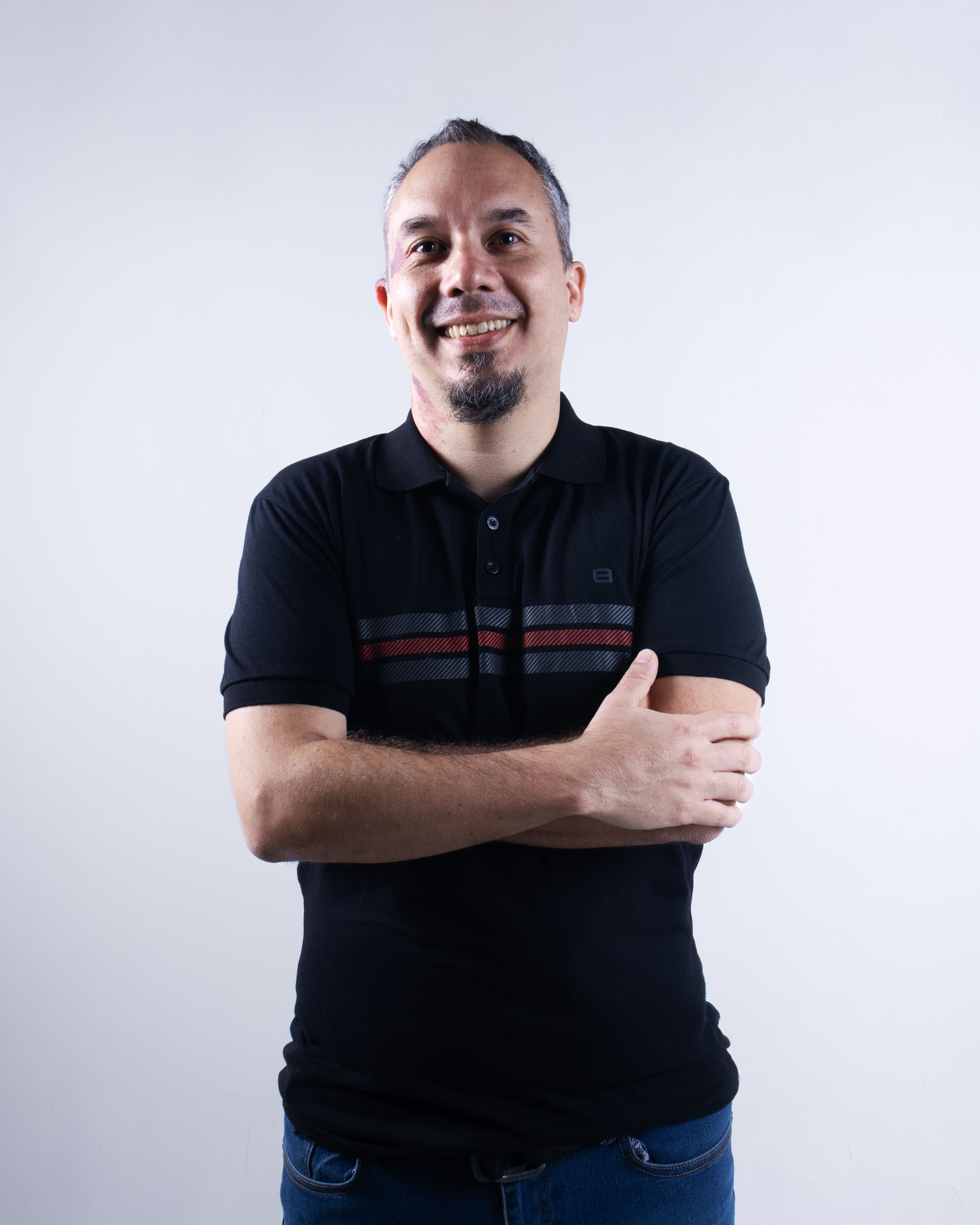 Happy man in casual attire standing against a neutral background.