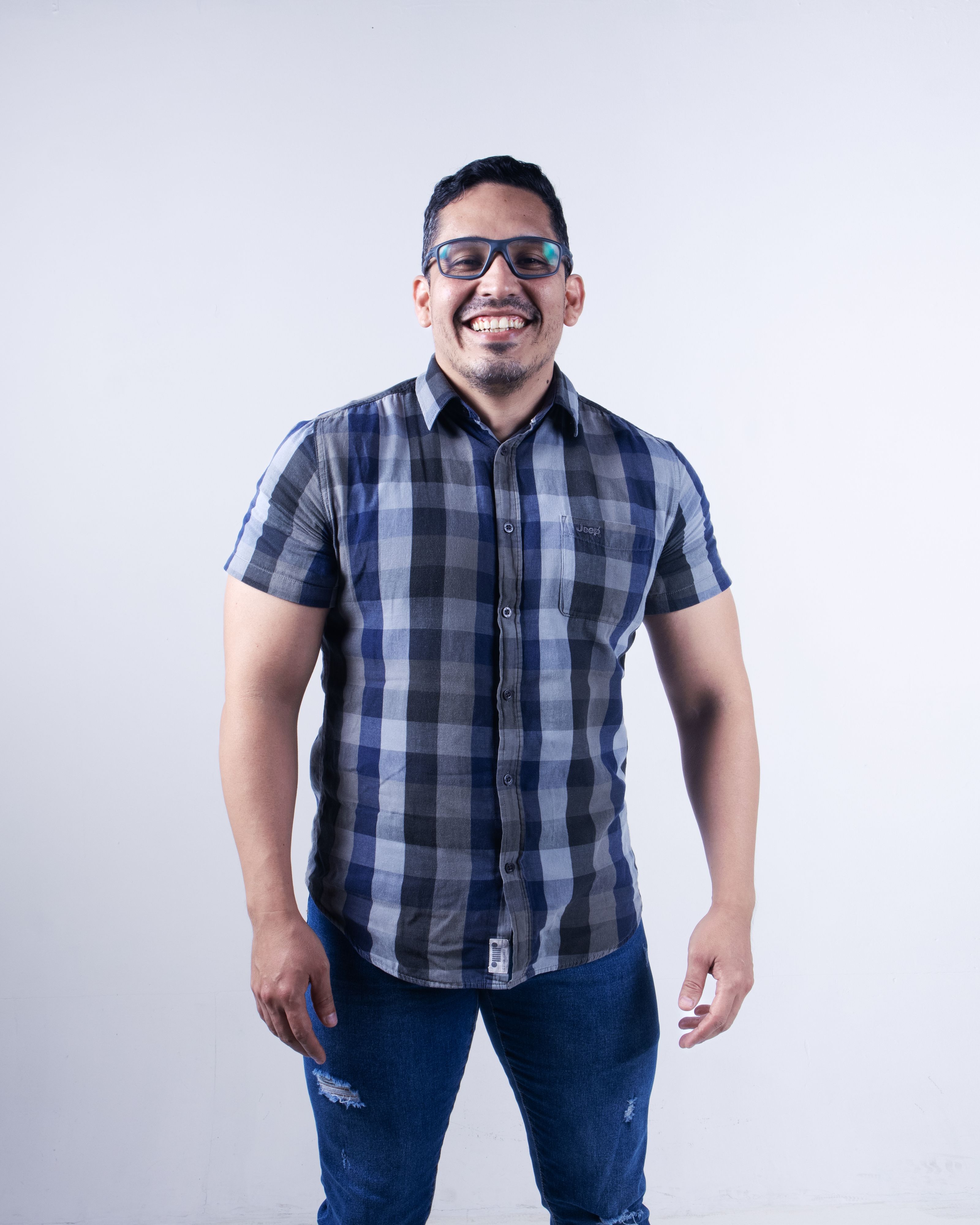 Homem feliz usando óculos e camisa xadrez sorrindo para a câmera.