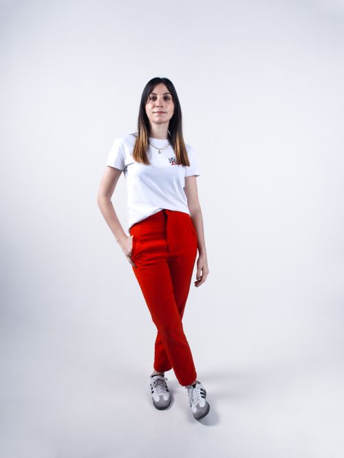 Free Stylish young woman in red pants and white shirt posing in a studio with a bright backdrop. Stock Photo