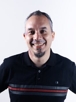 Portrait of a smiling man wearing a black polo shirt against a white background.