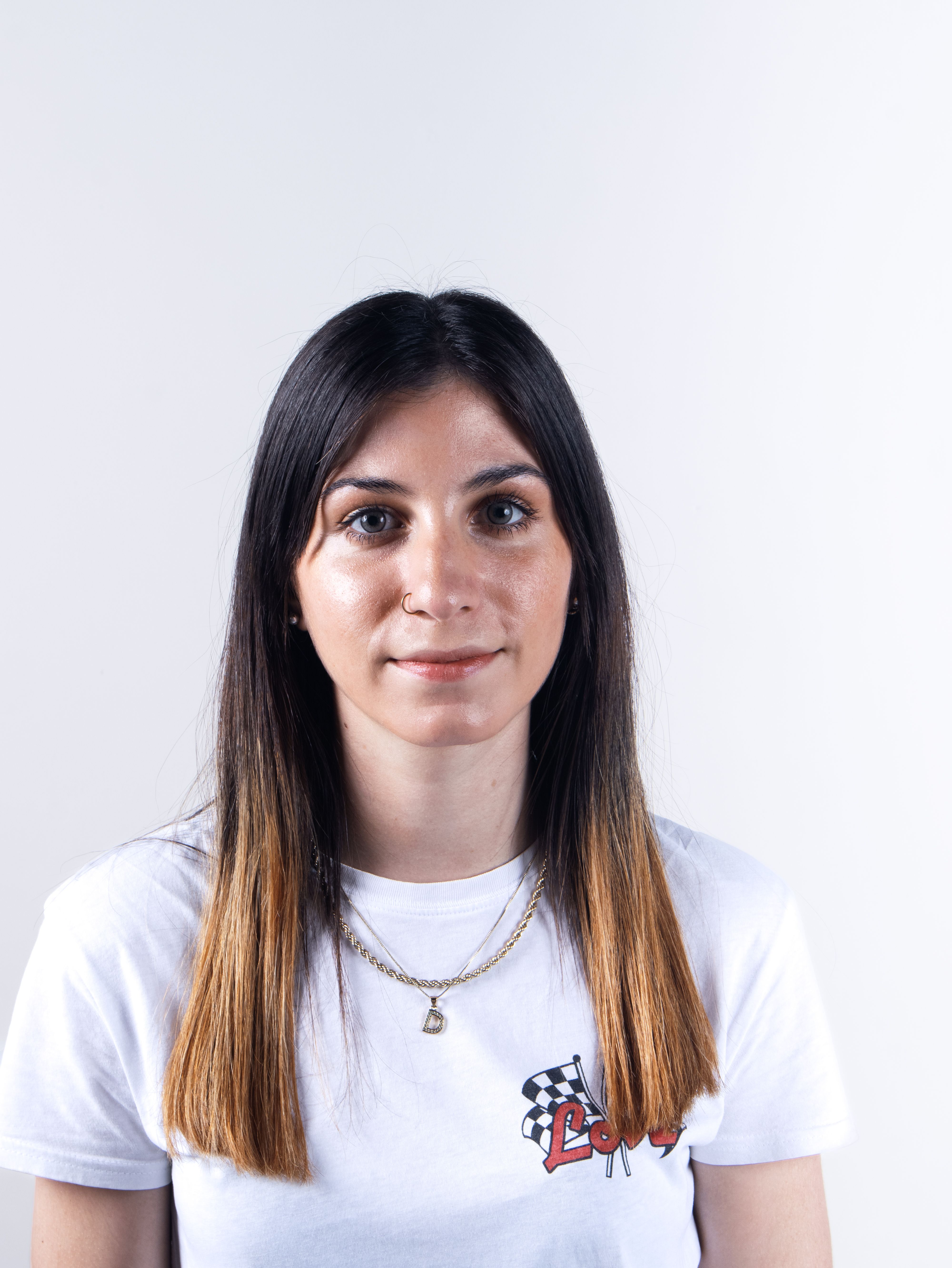 A woman in a white shirt poses casually against a plain background.