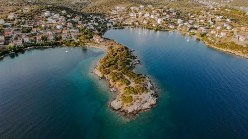 Free A stunning aerial view of a coastal peninsula surrounded by clear blue waters and a quaint village. Stock Photo