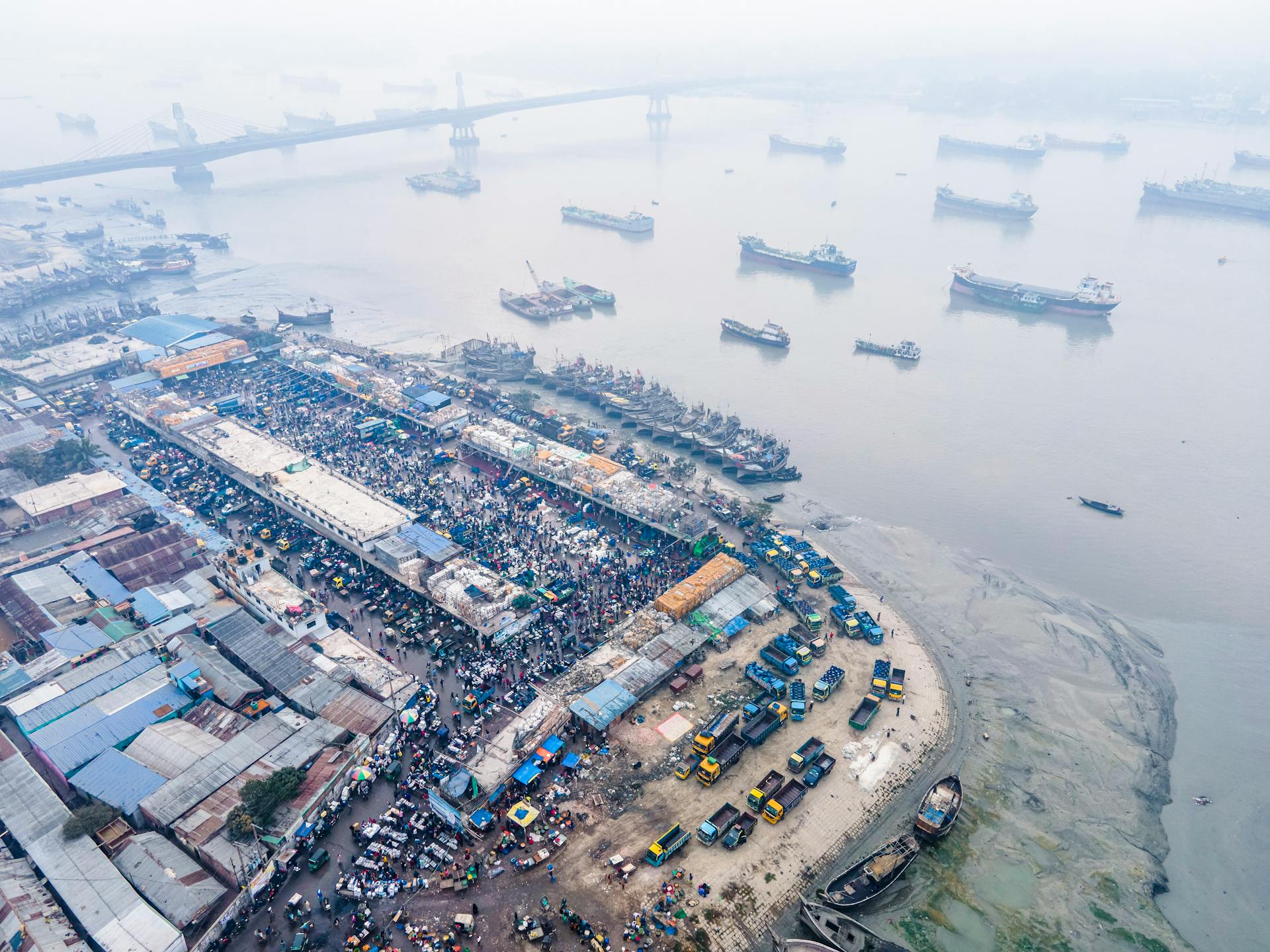 Aerial photo showcasing bustling activity at Chittagong's industrial port with ships and trucks.