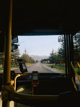 View from a bus front window showing a scenic road with trees and mountains
